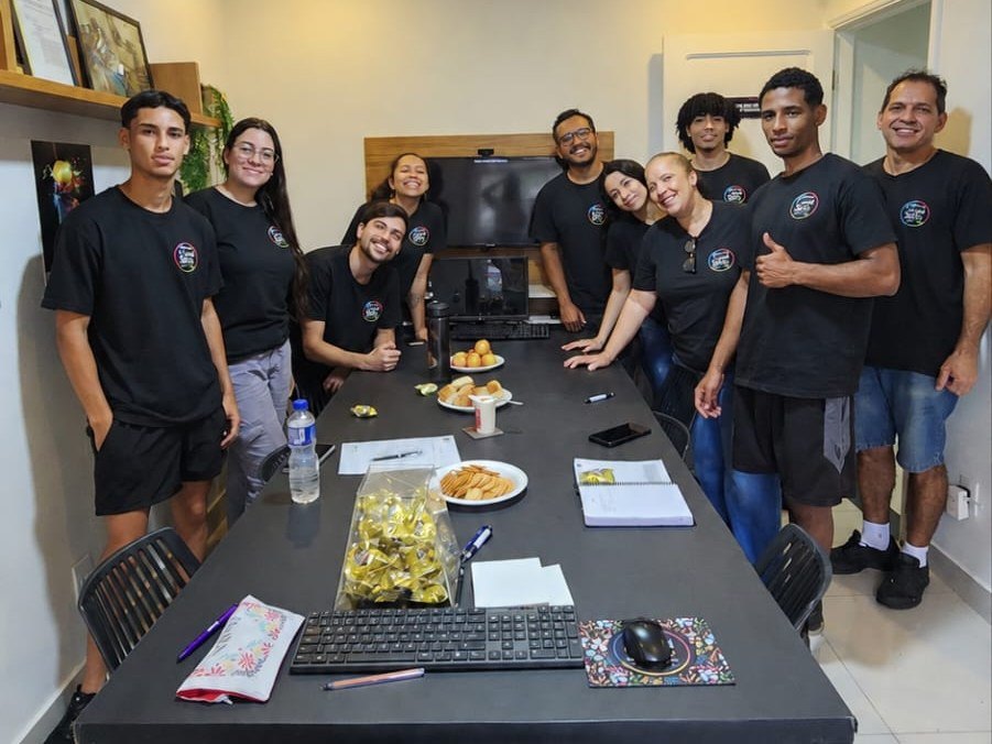 Equipe da Gráfica Canal Sete de uniforme, reunida na sala da loja